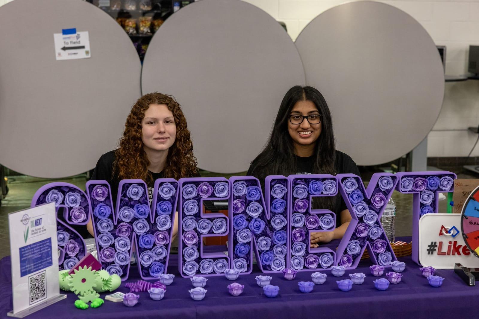 Two students staffing a SWENext outreach table at a FIRST Tech Challenge semi-regional